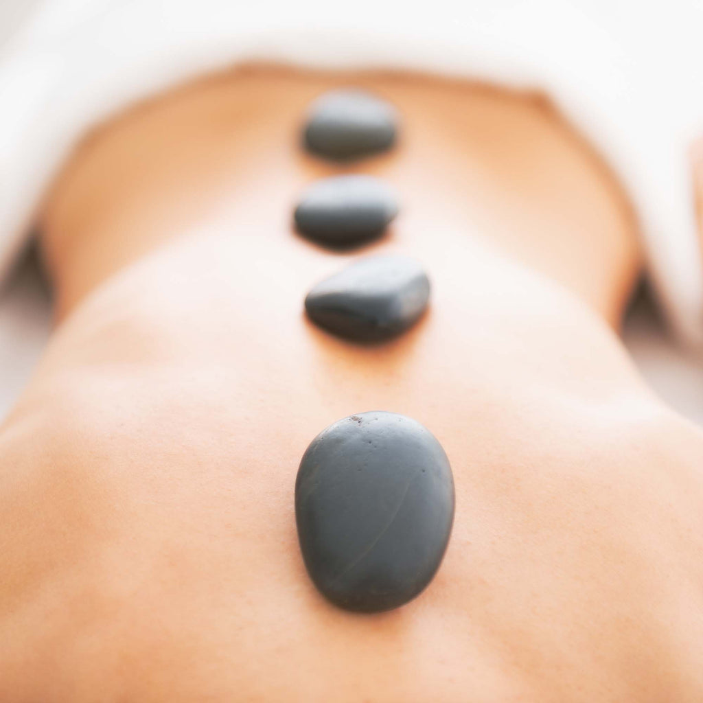 Woman's bare back with a row of hot black stones sitting in a line
