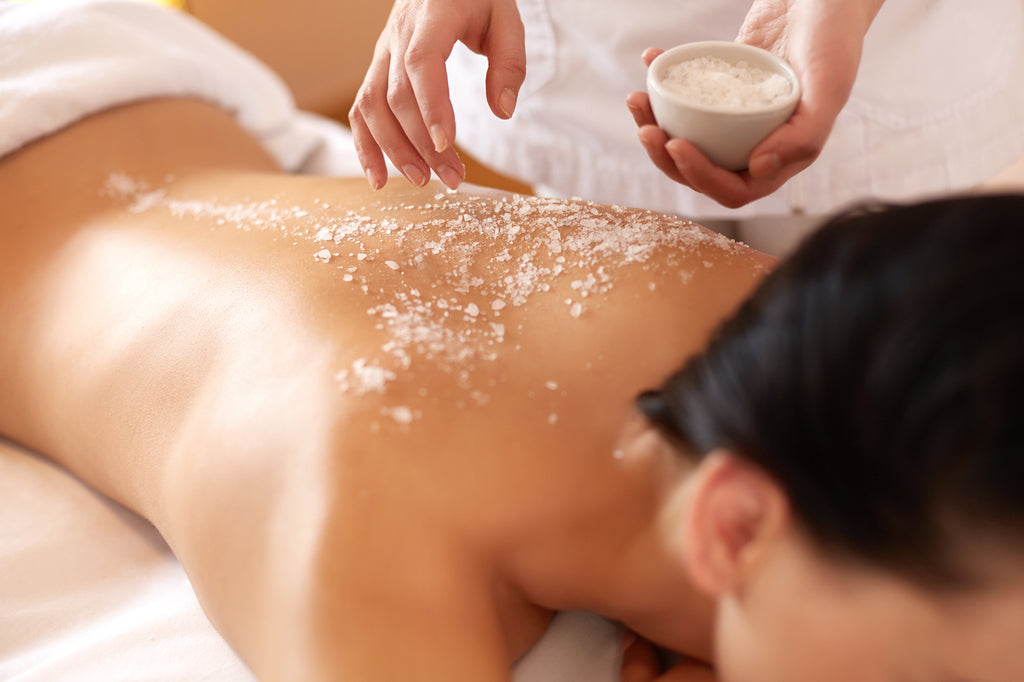 A woman with black hair getting salt sprinkled on her bare back