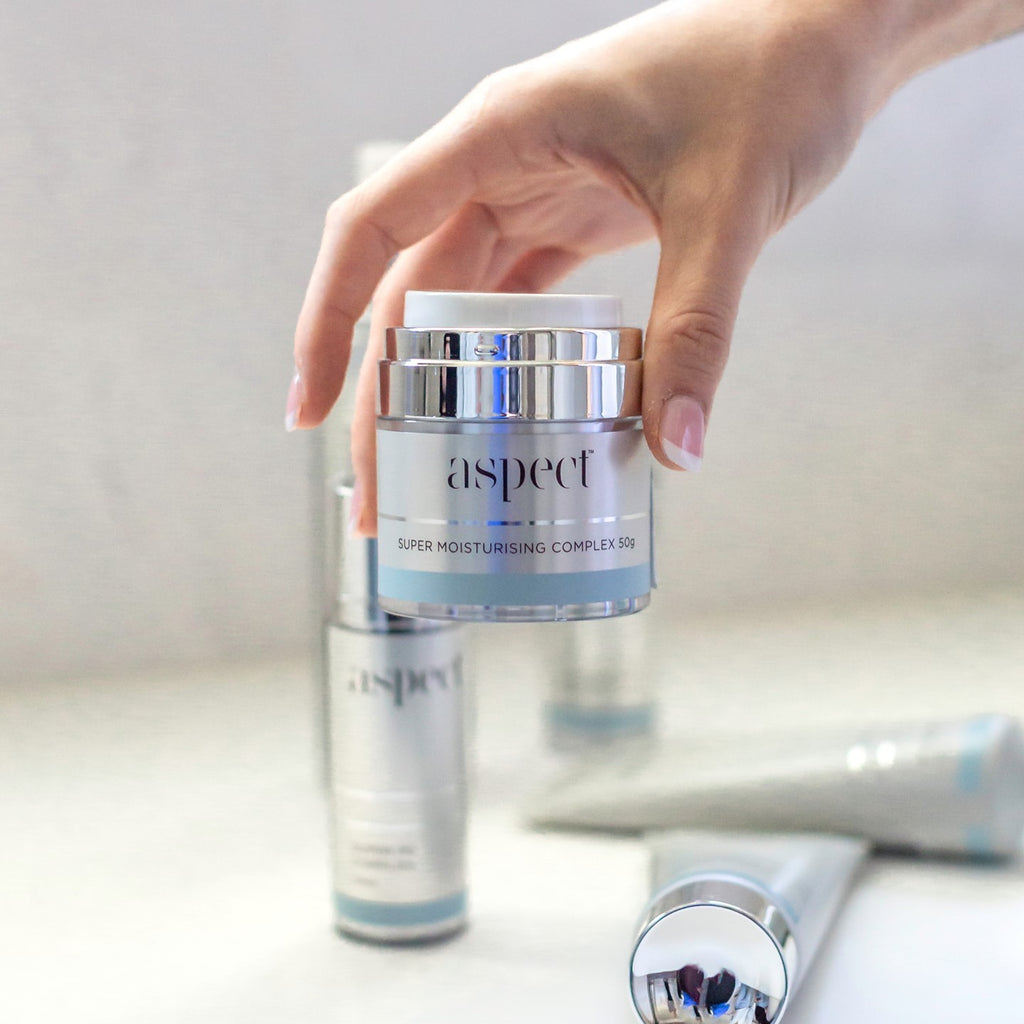 Aspect skincare super moisturising complex container being held by a woman's hand among other aspect skincare products