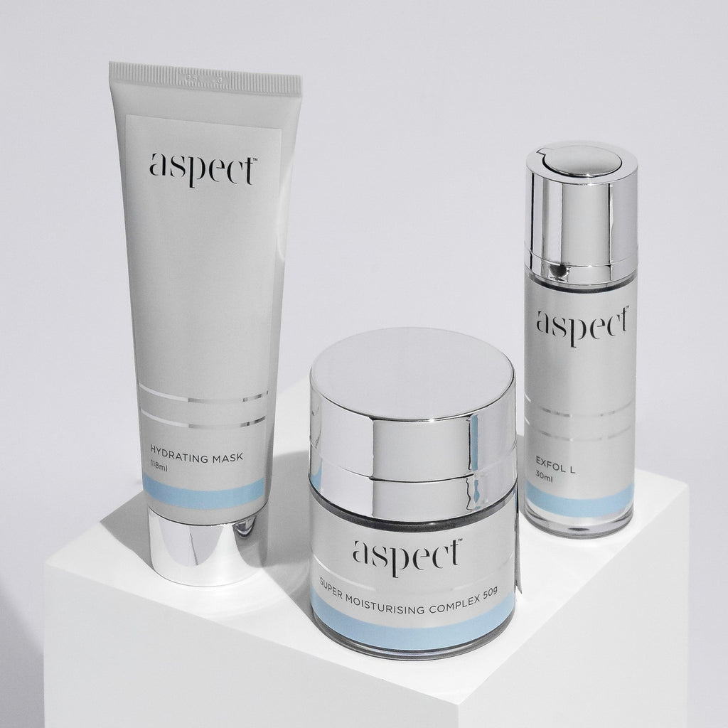 Three aspect skincare products in grey containers on top of white platform in front of white background