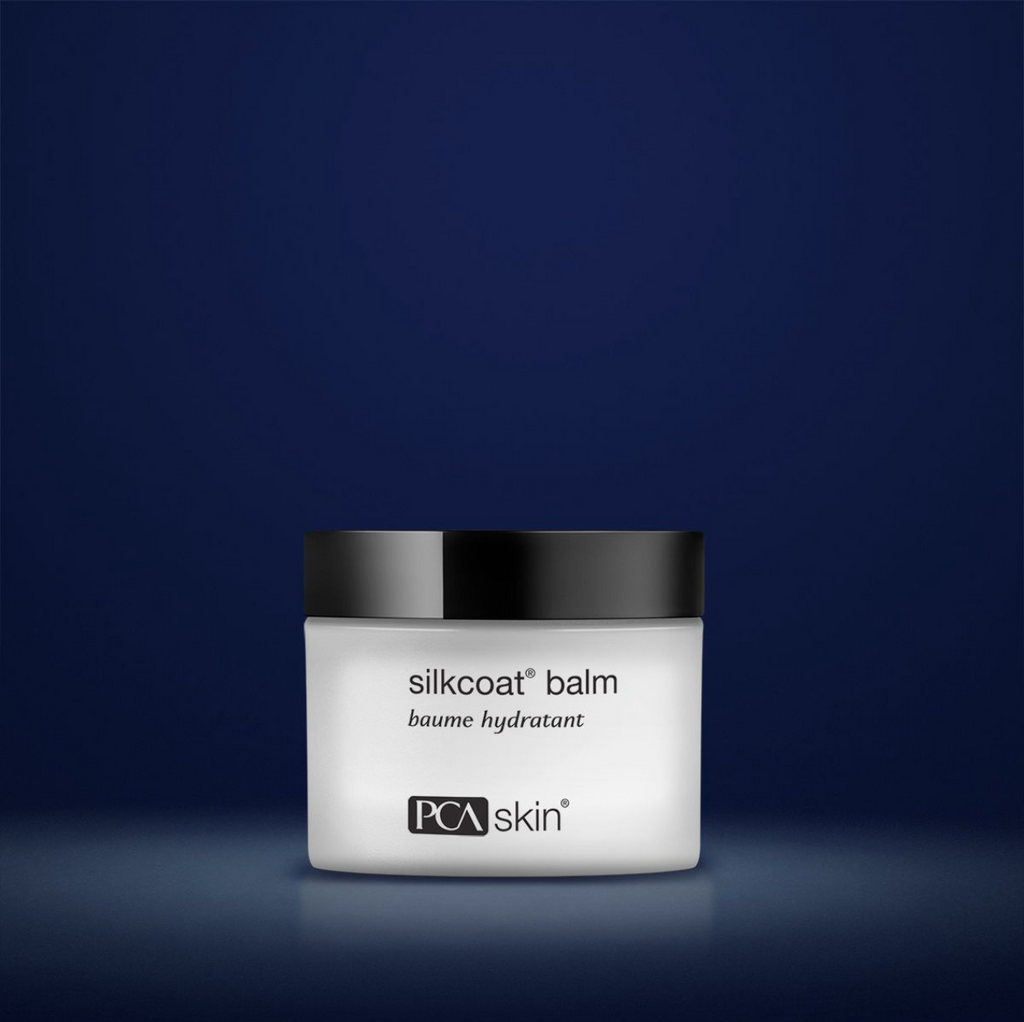 PCA silkcoat balm in white container with black lid in front of dark blue background