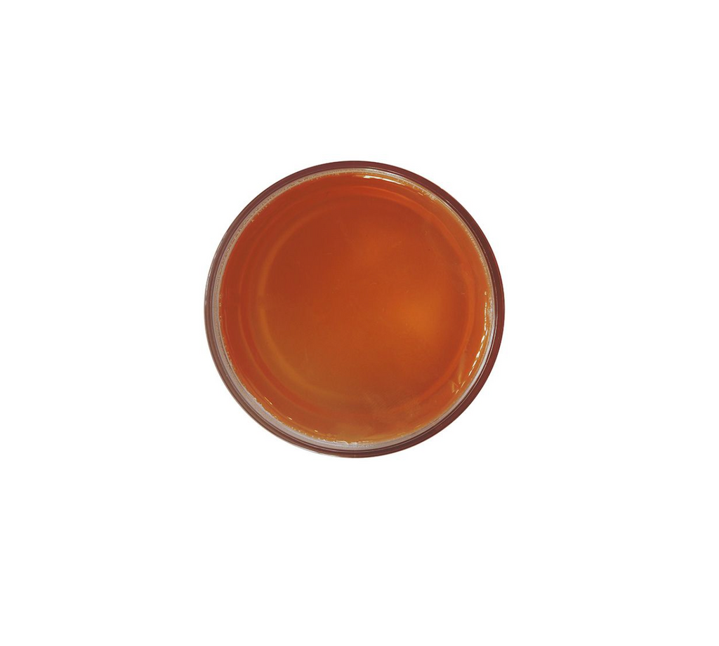 orange substance in glass container from bird's eye view in front of white background